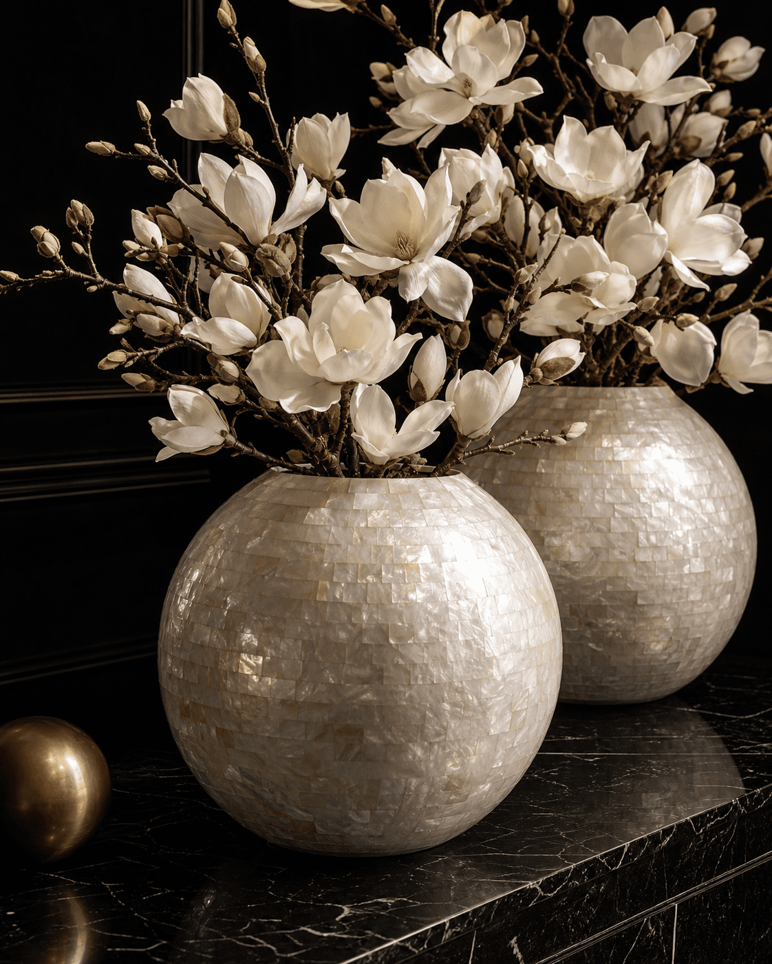Twee parelmoeren schelpenvazen met witte magnoliatakken
