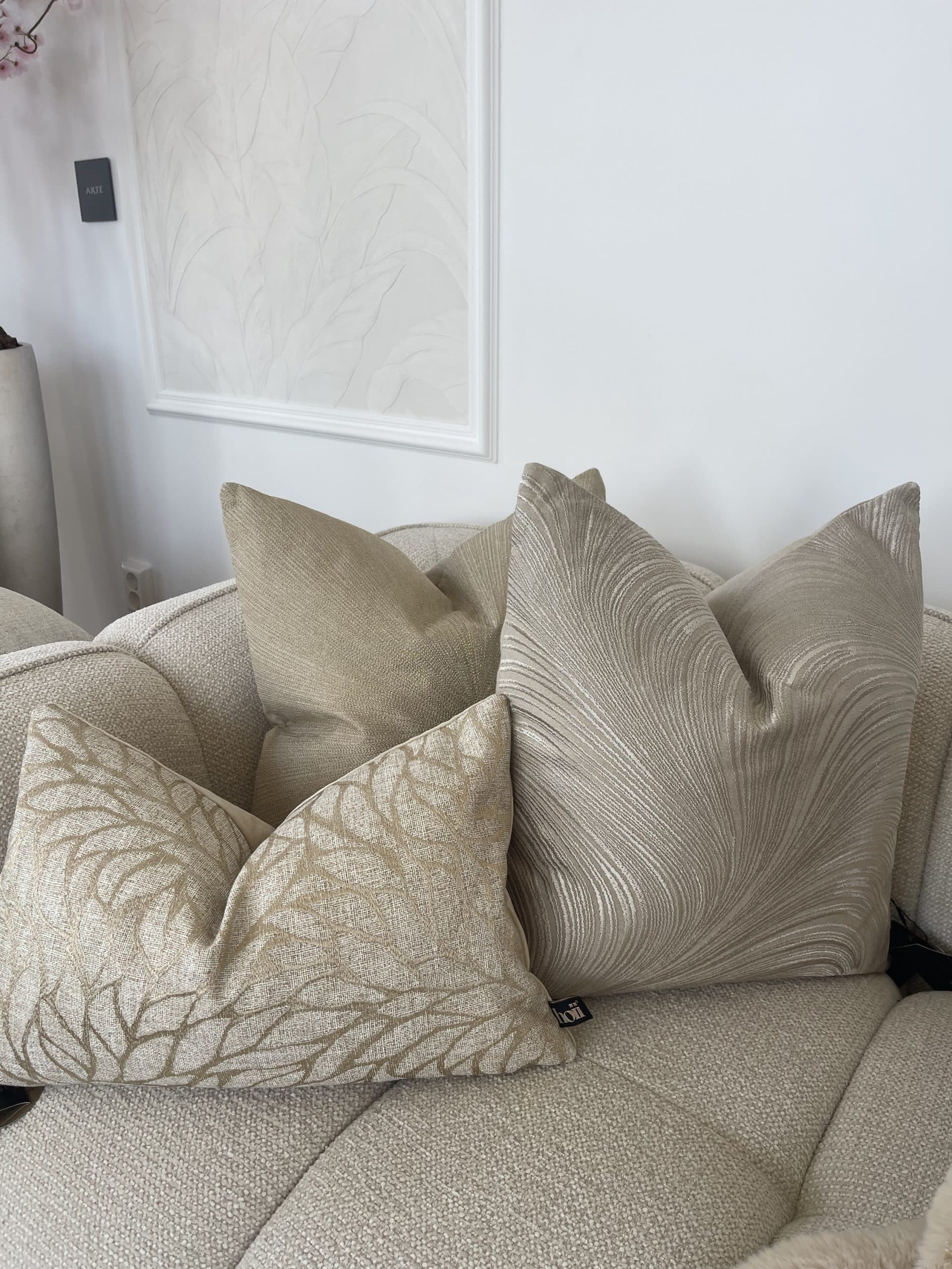 Sierkussens in beige en zandtinten met botanisch en golvend patroon op een bank