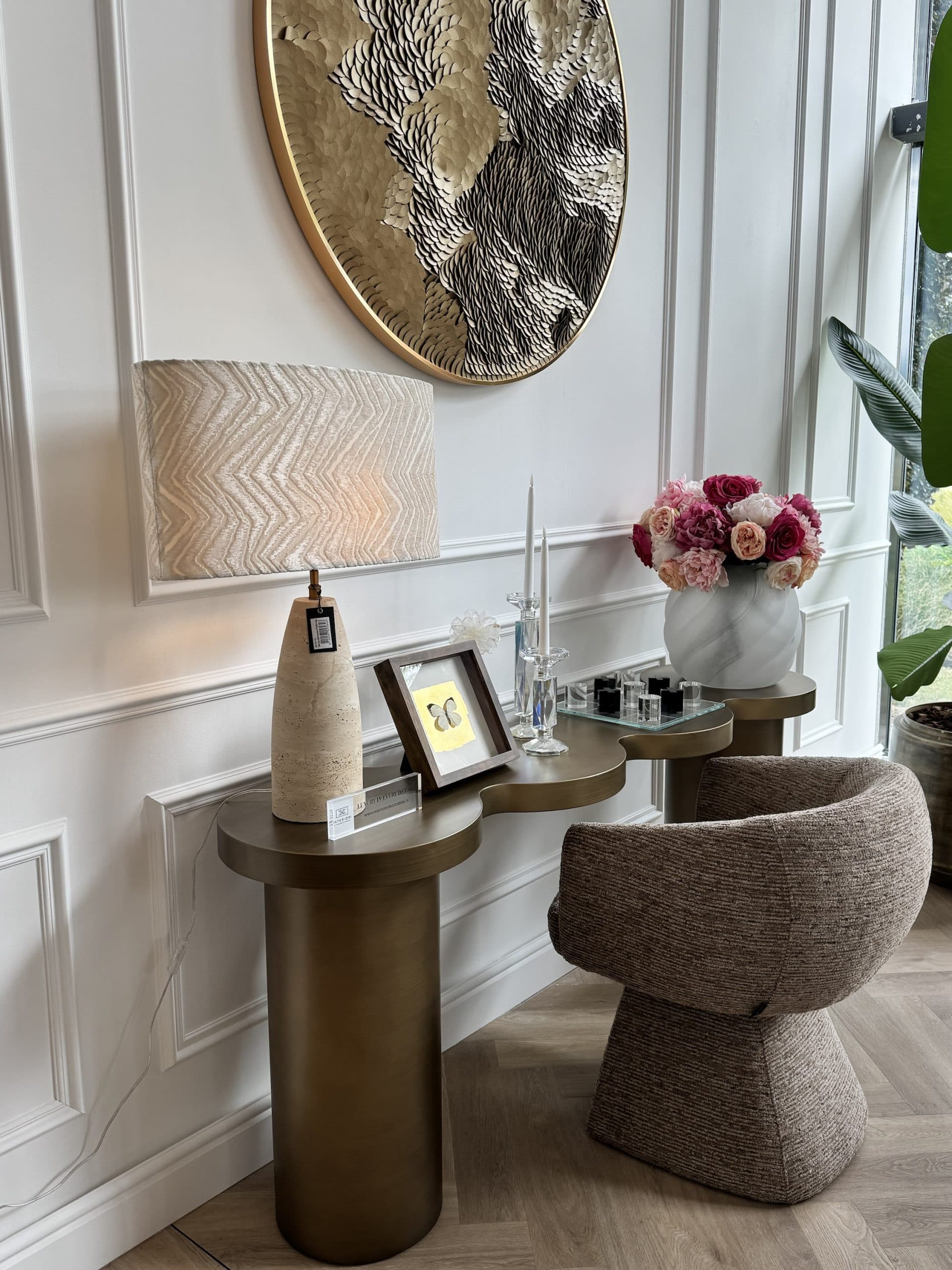 Brandende travertine tafellamp op een console in de woonkamer, naast een vaas met bloemen